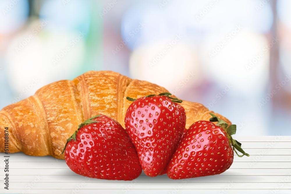 Tasty sweet Croissant with fresh strawberry on the desk