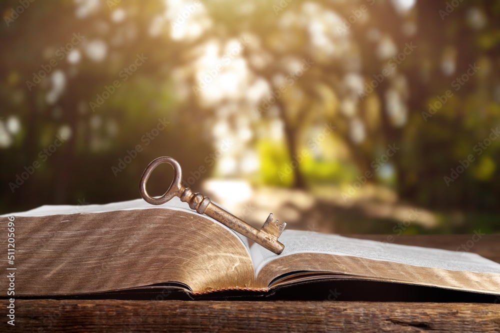 An open antique book on wooden table with vintage key