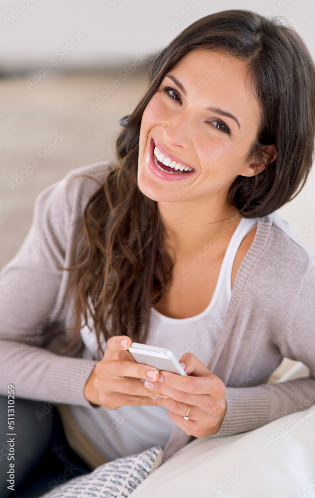 Texting a few friends to come over. Cropped portrait of a beautiful young woman relaxing at home.