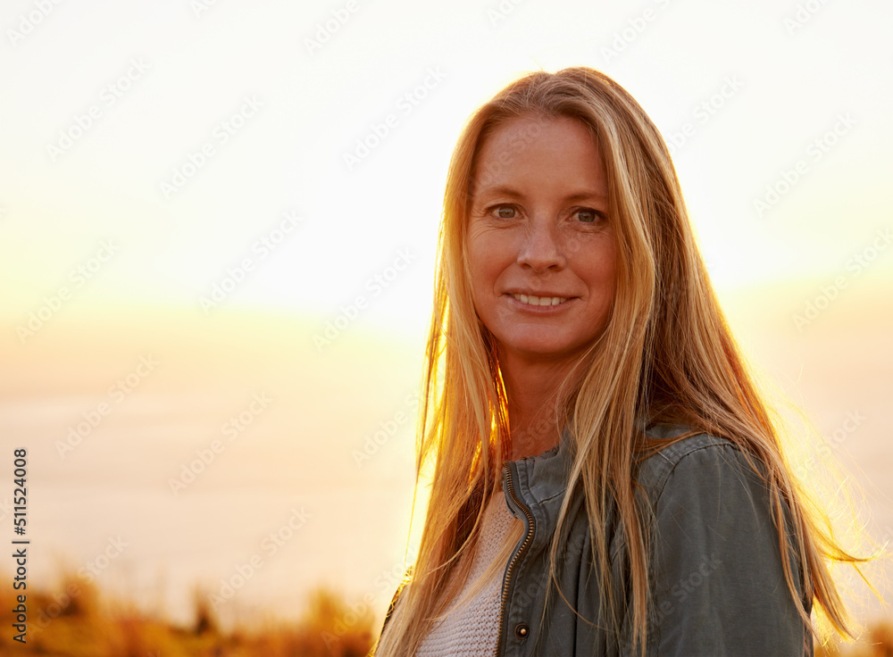 我最喜欢看日落的地方。一位美丽的年轻女子站在外面晒太阳的肖像