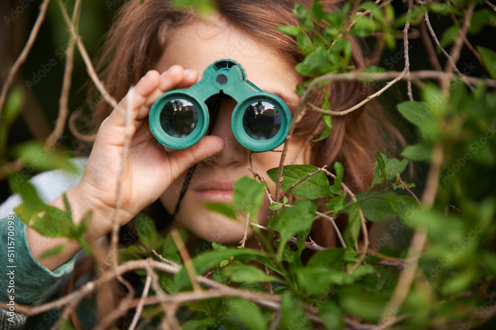 Bird watching is serious. Shot of a cute little girl looking through a pair of binoculars outdoors.