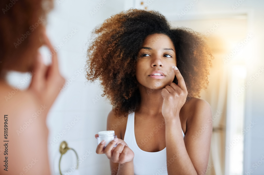 Making sure her skin stays hydrated all day. Shot of an attractive young woman applying moisturizer 