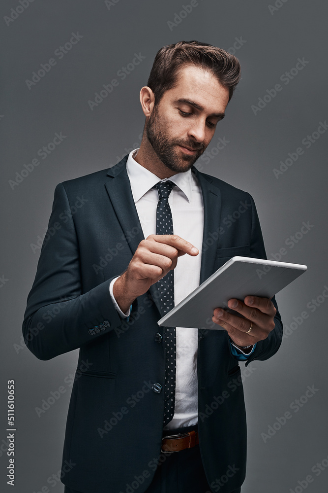 Linked to the corporate world. Studio shot of a handsome young businessman using a digital tablet ag