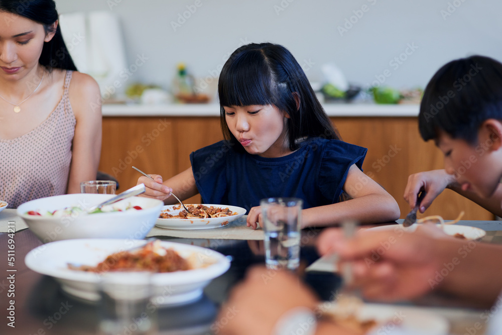 一大口的美味。两个小孩在家和妈妈一起吃饭的镜头。