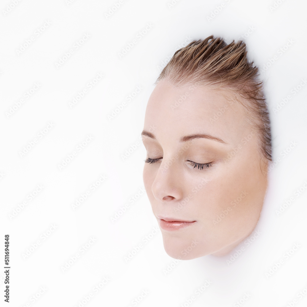 Totally immersive beauty. Studio shot of an attractive womans face emerging from a white liquid.