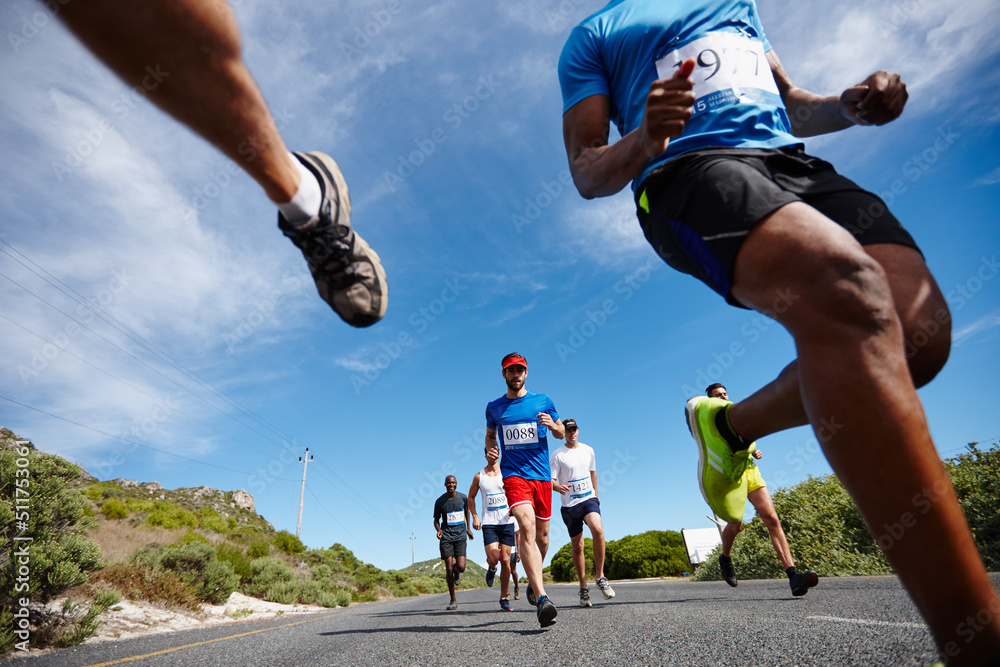 Running fast and free. Low angle shot of a group of young men running a marathon.