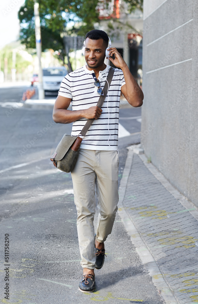 Enjoying his favorite playlist. A handsome african american businessman walking through the city whi