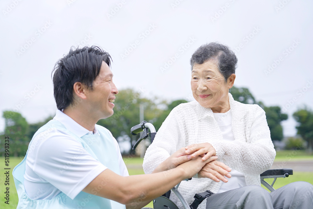 外で高齢者女性と会話する介護士