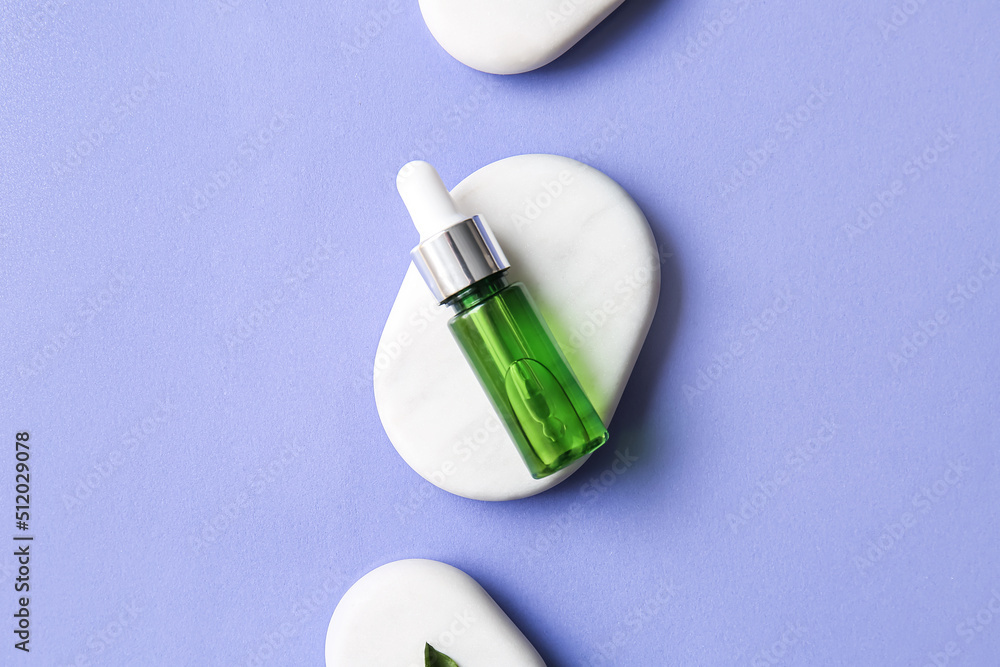 Bottle of natural serum and spa stones on lilac background