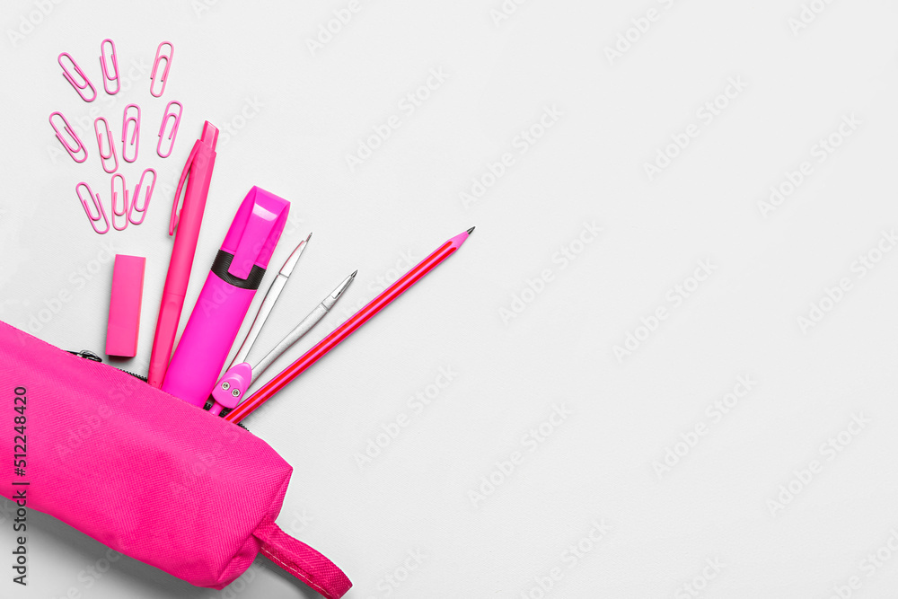 Pink pencil case with paper clips and stationery on light background