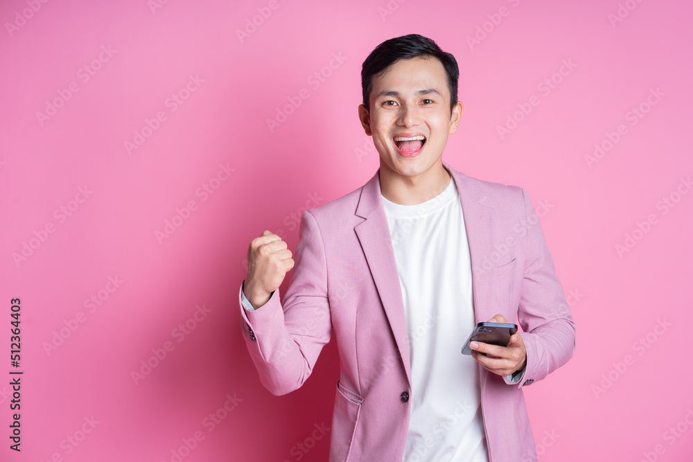 Portrait of young Asian man wearing pink suit posing on background