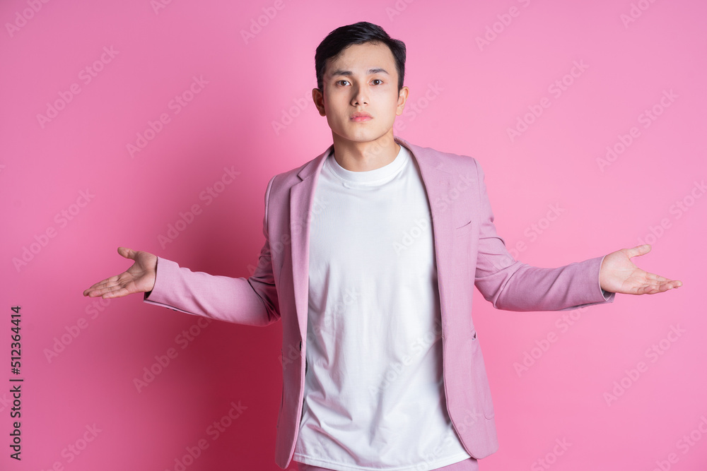 Portrait of young Asian man wearing pink suit posing on background