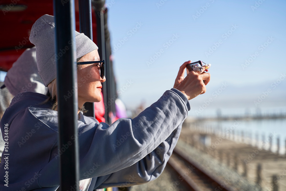 asian woman tourist taking a picture using cellphone on a sightseeing train