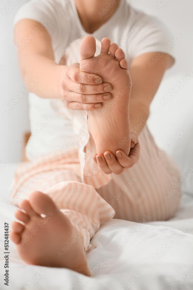 Young woman making foot massage on bed, closeup