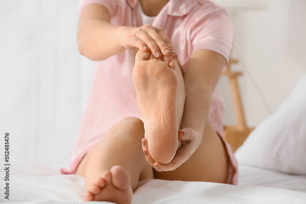 Young woman making foot massage on bed, closeup