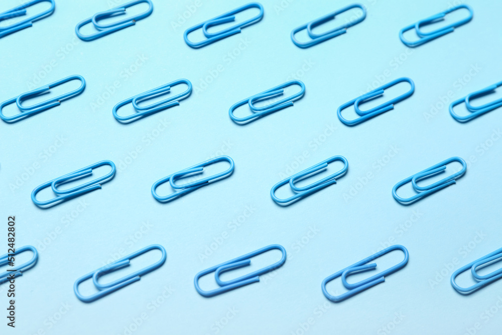 Blue paper clips on color background