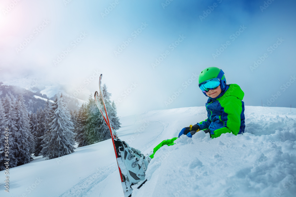 滑雪男孩坐在雪地里的侧视图