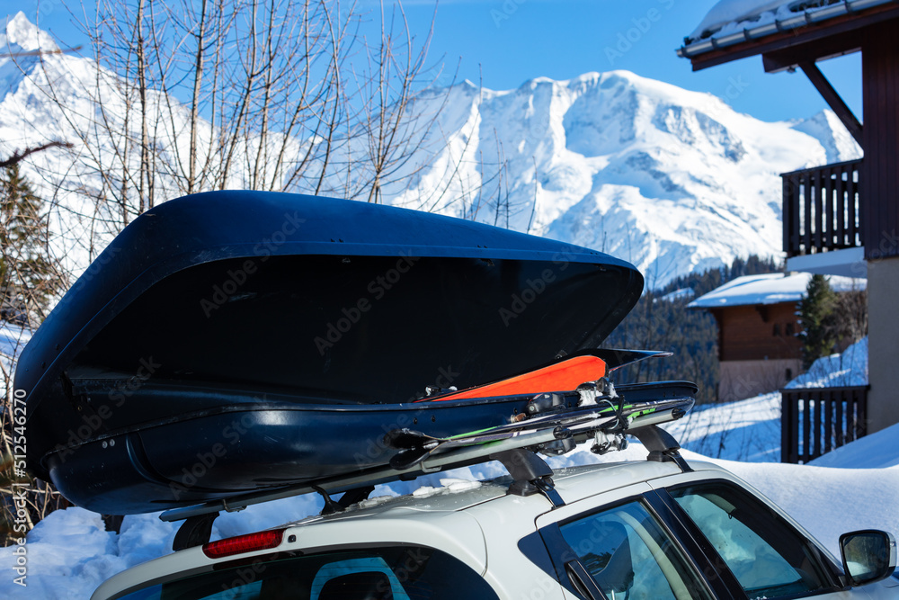 Car box on the roof with ski inside over mountain peaks