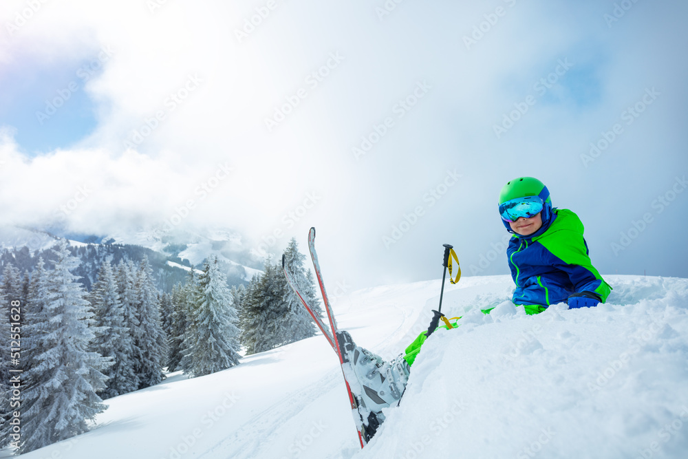 高山滑雪男孩坐在雪地里的侧视图