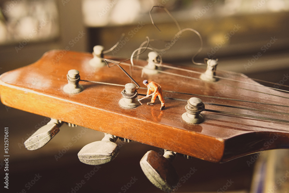 The technician worker figure fixing old guitar strings.