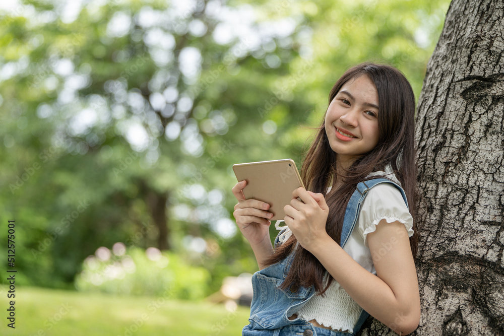 公园里体贴的微笑女人使用智能数字平板电脑，一位年轻迷人的商业女性的画像