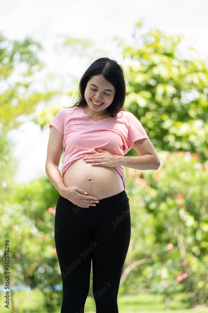 孕妇在城市公园摸肚子，孕妇放松和锻炼，美丽温柔的麋鹿