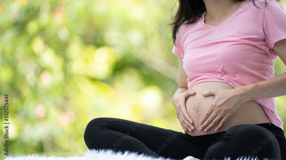 Pregnant woman touching belly in the City Park, Pregnant Relaxing and exercise, Beautiful tender moo