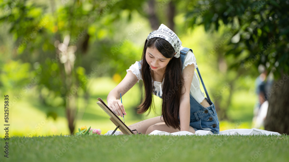 迷人的女孩，在阳光明媚的夏日，坐在公园的格子布上，用水彩完成