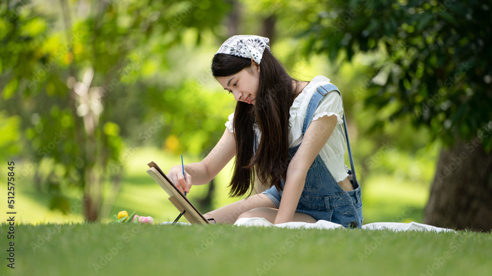 迷人的女孩，在阳光明媚的夏日，坐在公园的格子布上，用水彩完成