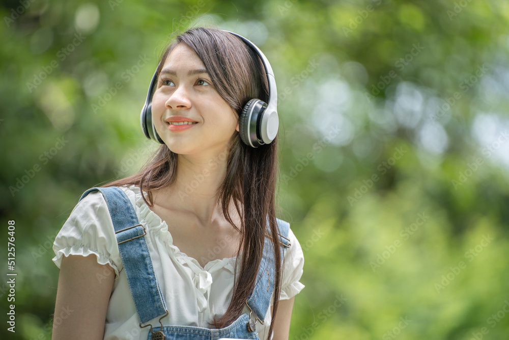 身穿米色衬衫的美丽年轻女子在绿城公园背景中摆姿势，微笑女孩Listenin