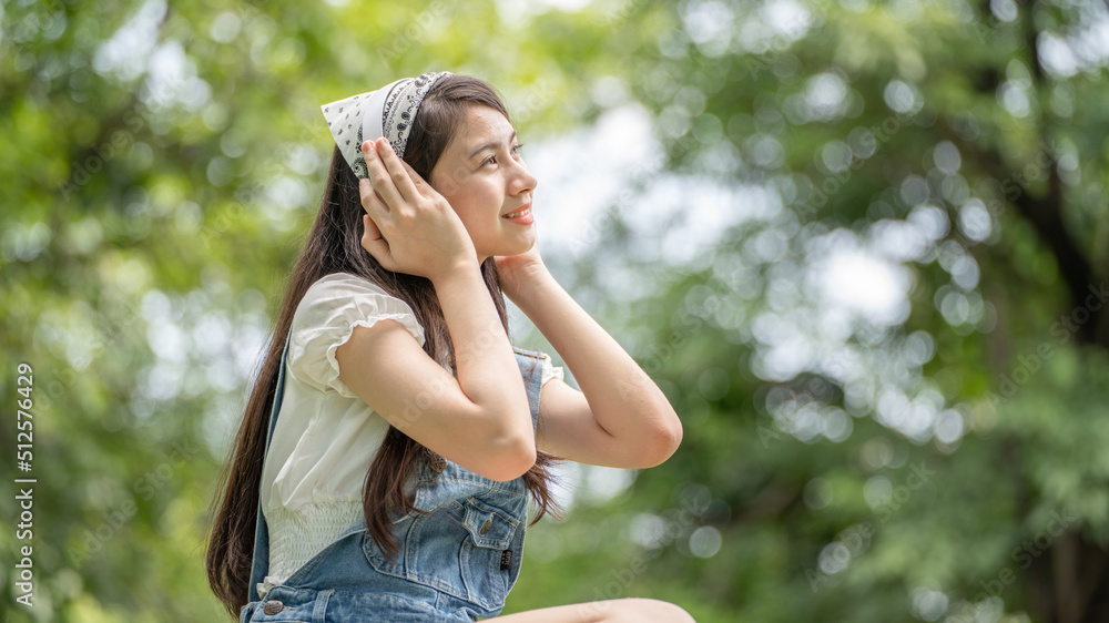 身穿米色衬衫的美丽年轻女子在绿城公园背景中摆姿势，微笑女孩Listenin