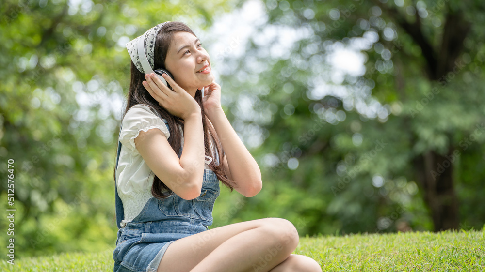 身穿米色衬衫的美丽年轻女子在绿城公园背景中摆姿势，微笑女孩Listenin