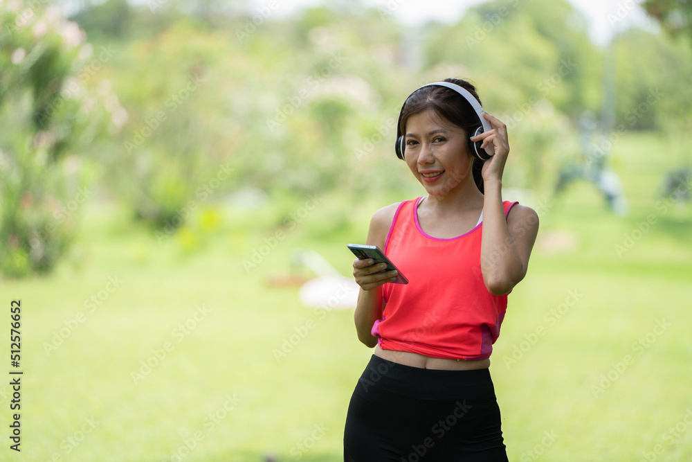 身穿米色衬衫的美丽年轻女子在绿城公园背景中摆姿势，微笑女孩Listenin