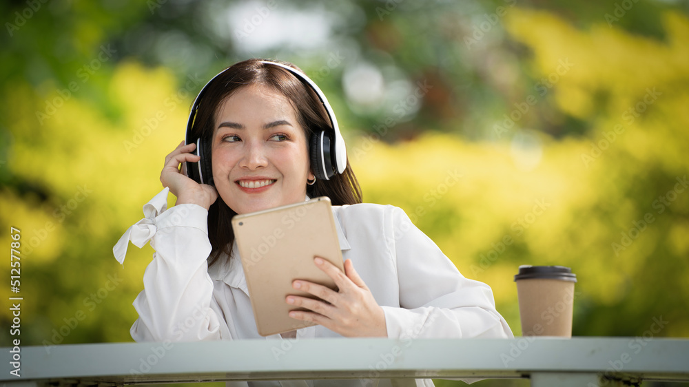 身穿米色衬衫的美丽年轻女子在绿城公园背景中摆姿势，微笑女孩Listenin