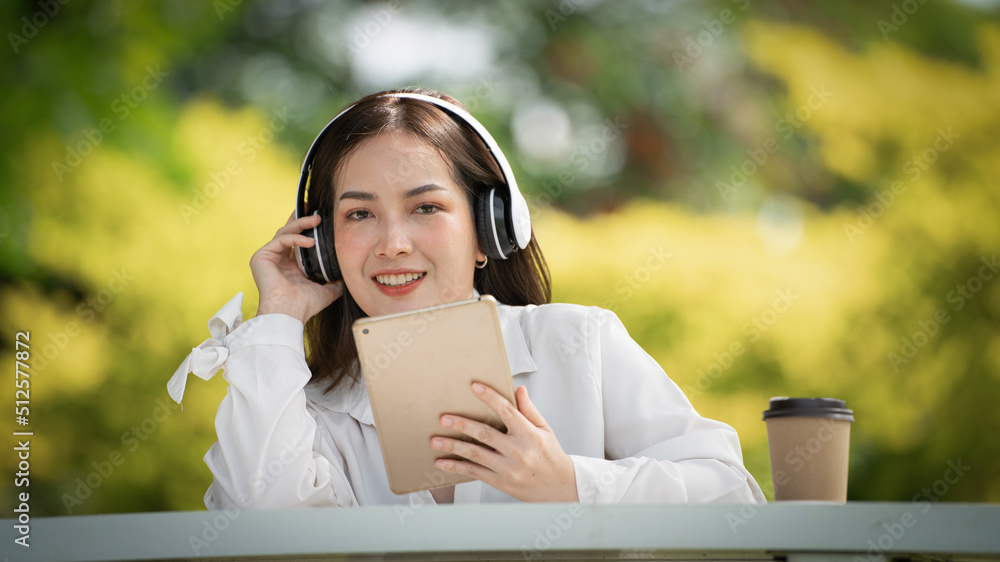 身穿米色衬衫的美丽年轻女子在绿城公园背景中摆姿势，微笑女孩Listenin