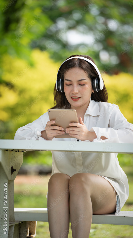 身穿米色衬衫的美丽年轻女子在绿城公园背景中摆姿势，微笑女孩Listenin