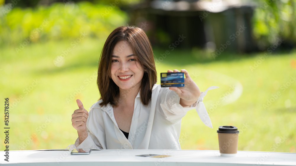 购物者微笑女孩坐在本上用智能手机和信用卡在网上购物或工作