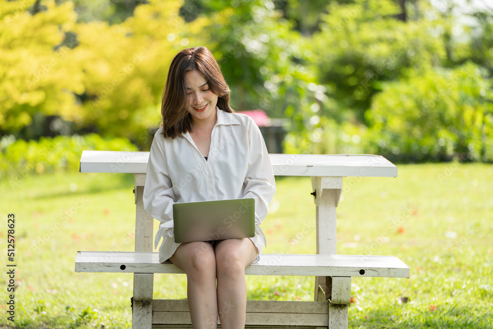 公园里体贴的微笑女人使用智能数字平板电脑，一位年轻迷人的商业女性的画像