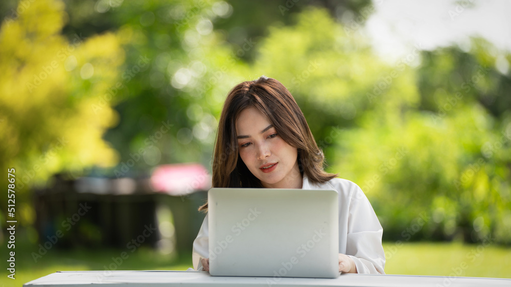 公园里体贴的微笑女人使用智能数字平板电脑，一位年轻迷人的商业女性的画像