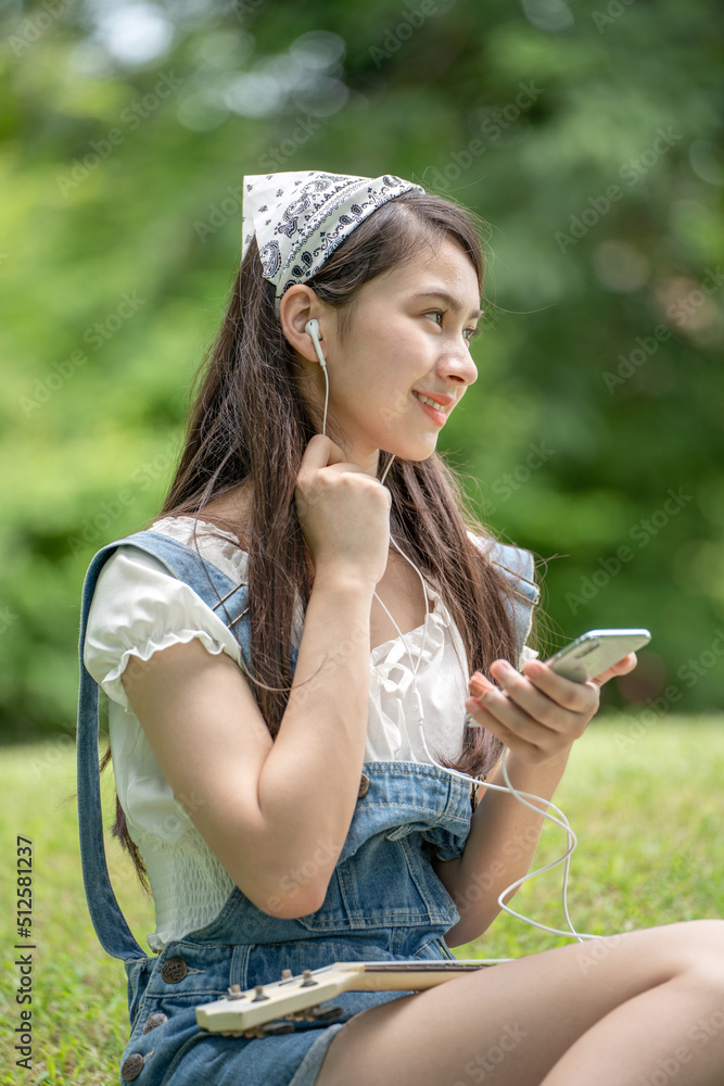 身穿米色衬衫的美丽年轻女子在绿城公园背景中摆姿势，微笑女孩Listenin