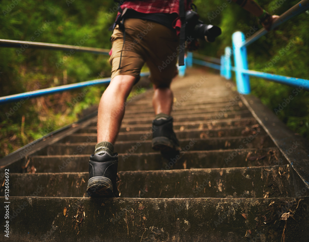 This trail is no challenge for him. Rearview shot of a man climbing stairs while hiking in the mount