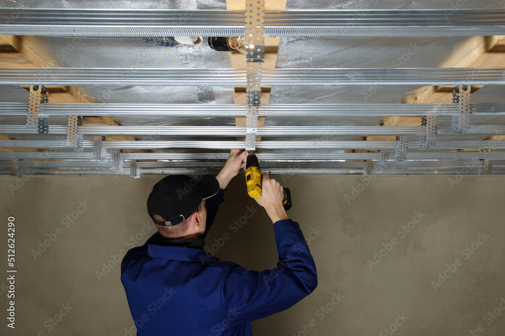 Man assembles profile metal frame for plasterboard