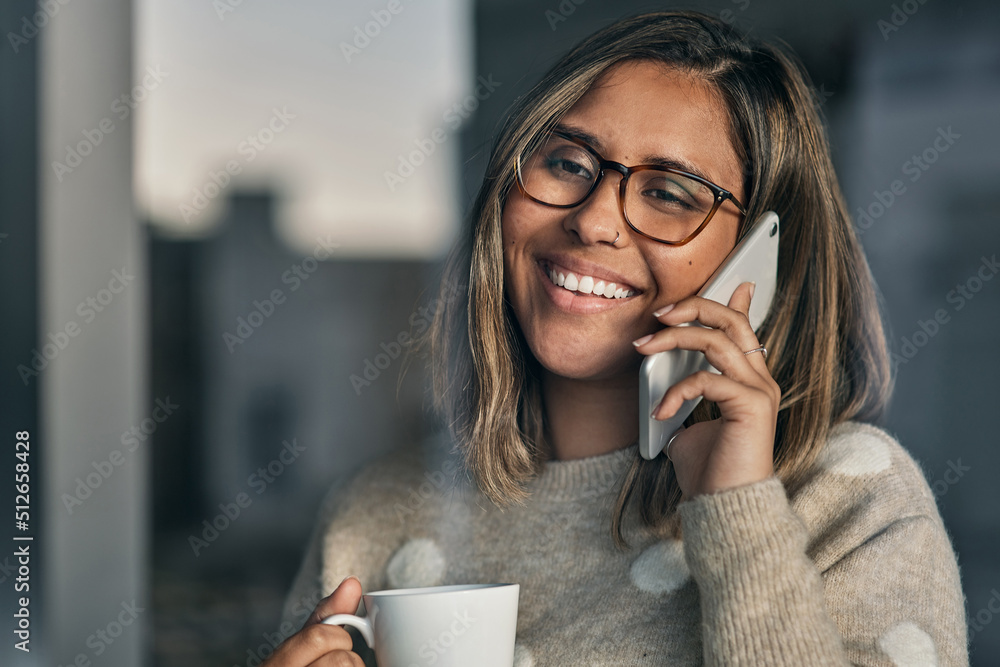 Ive been waiting for your call. Shot of a woman holding a cup of coffee while talking on her cellpho