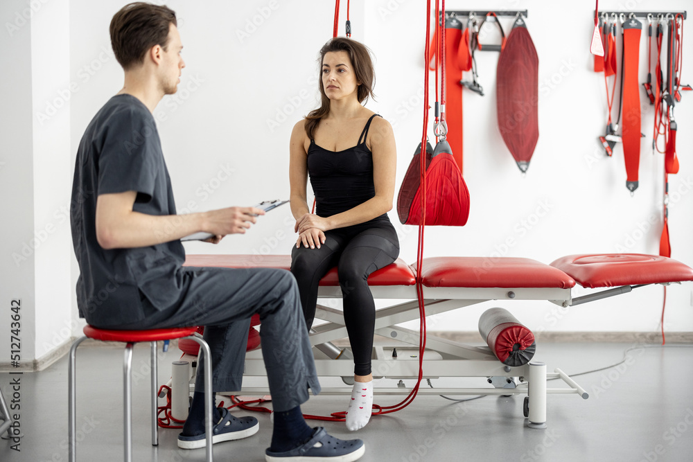 Woman having consultation with rehabilitation specialist or physiotherapist before active treatment 