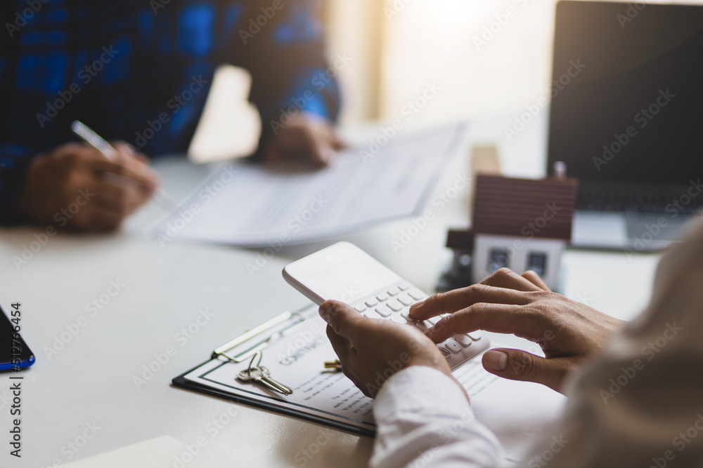 Real estate agents are discussing a mortgage on a house, land plot and calculating interest on a rea