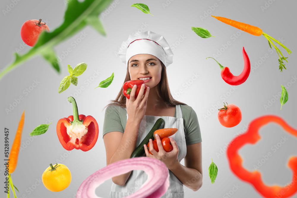 Young chef with flying fresh vegetables on grey background