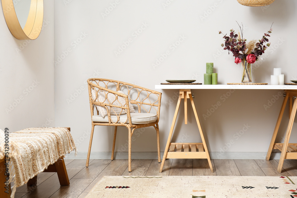 Comfortable armchair and served dining table near light wall