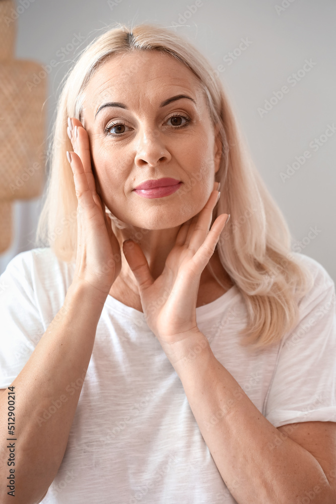 Morning of mature woman applying facial cream at home