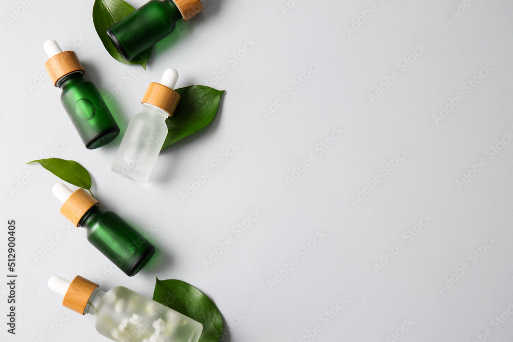 Composition with different bottles of serum and plant leaves on white background