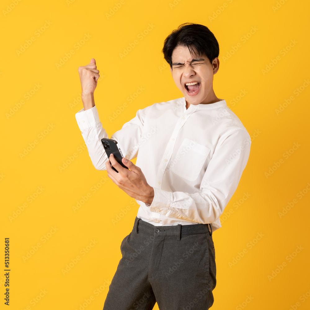 Young good looking asian man using smartphone isolated on yellow background surprising